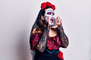 Young woman wearing day of the dead costume over white shouting angry out loud with hands over mouth