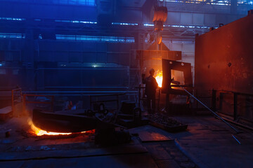 Worker operates metal casting process in metallurgical plant
