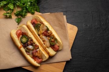 Hot dog with jalapeno pepper, bacon and caramelized onion on dark background