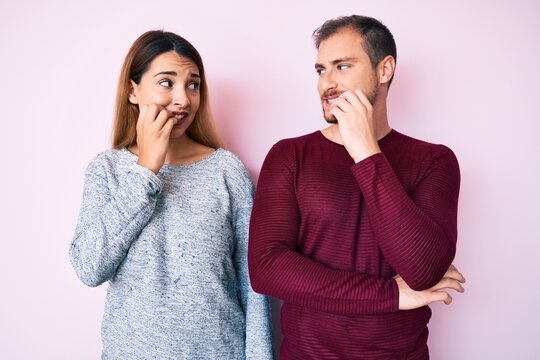 Beautiful couple wearing casual clothes looking stressed and nervous with hands on mouth biting nails. anxiety problem.