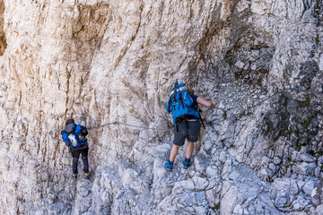 two experienced female hikers are climbing a rocky wall in the Dolomites