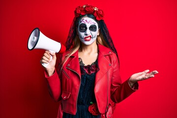 Woman wearing day of the dead costume using megaphone clueless and confused expression. doubt concept.
