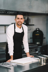 Portrait of a Professional chef posing and wearing  uniform and gown in kitchen