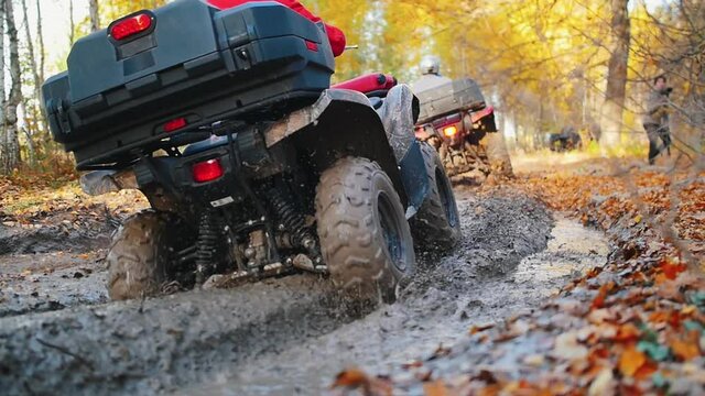 Outdoor activity - people riding ATVs in the forest - ride in the mud