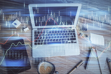 Double exposure of financial chart drawing over table background with computer. Concept of research...