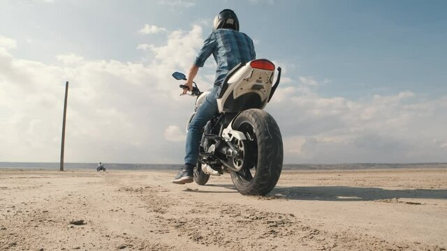 Motorcyclist doing tire burnout on customized motorcycle in the desert, slow motion. Professional motorcyclist drift on sport bike on a dry salt lake and ride away