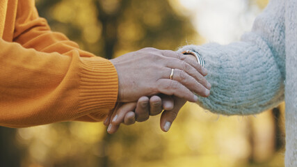 close up wrinkled hands. Happy old couple hugging in park. Senior man flirting with elderly woman....