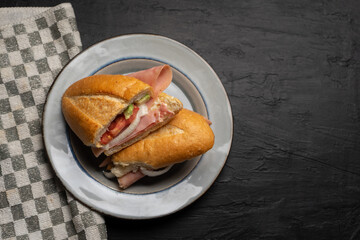 Mexican ham sandwich with avocado and cheese also called torta on dark background