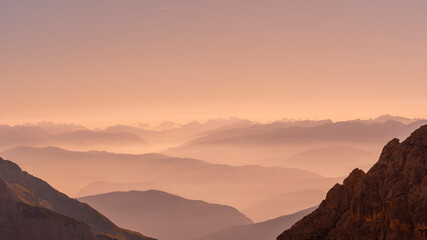 fog at sunrise over the mountain ranges of the dolomites