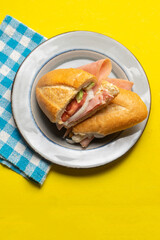 Mexican ham sandwich with avocado and cheese also called torta on yellow background