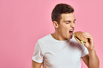 man with big hamburger on pink background calories fast food cropped view Copy Space close-up