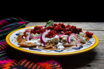 Mexican enfrijoladas with chorizo and cheese on wooden background