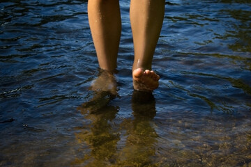 Legs of a young woman walking by the sea. Young woman's barefoot walking in the stream. Front view.