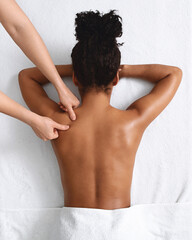African american naked woman getting relaxing back massage on white
