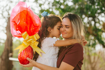 Obraz premium Latin family celebrating Easter. Curly girl hugging her mother on a sunny day in the park
