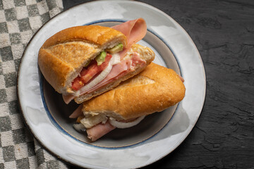 Mexican ham sandwich with avocado and cheese also called torta on dark background