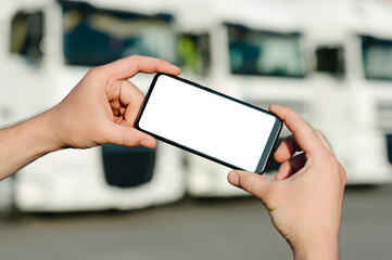 Mock up of a smartphone in the hands of a man. Against the backdrop of trucks. Logistics concept.