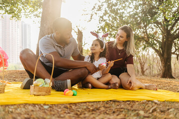 Latin family celebrating Easter. curly girl wearing bunny ears and painting an easter egg
