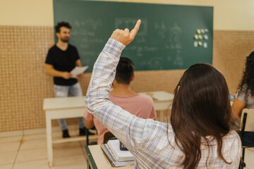 Latin students in the classroom. back view of female student asking questions in class
