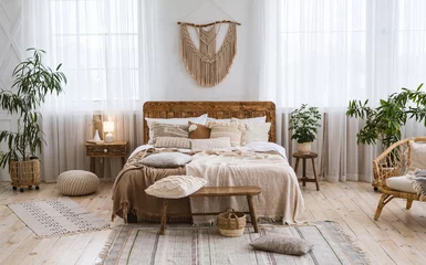 Fotobehang Boho Rustiek huisontwerp met etnische boho-decoratie. Bed met kussens, houten meubels  © Prostock-studio