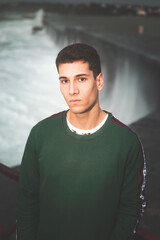 Young caucasian boy posing next to a brave sea.