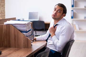 Young male employee unhappy with excessive work in the office