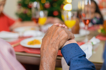 Summer Christmas dinner in Brazil. Real Brazilian family having fun at the Latin American Christmas party. family praying. closed up hand of elderly man praying