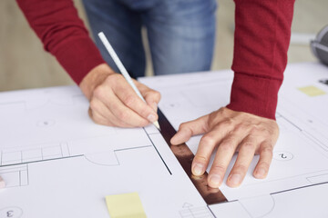 Closeup background of unrecognizable architect drawing blueprints while leaning on desk at workplace, copy space