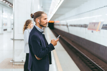 subway passengers wait for the train to arrive,standing at a safe distance.