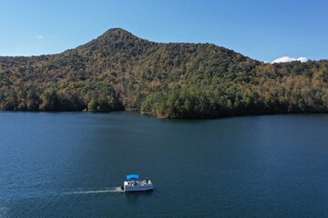 Aerial image of Funnel Top mountain and Lake Santeetlah, North Carolina in autumn color with pontoon boat in foreground.