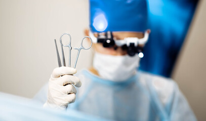 male surgeon holds in hand surgical instruments tweezers and scissors clamps.