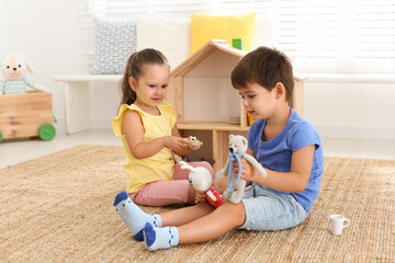 Cute little children playing with toys near wooden house on floor at home