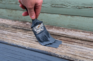 Womens hands Painting faded old Garden Wooden Decking With Grey Paint