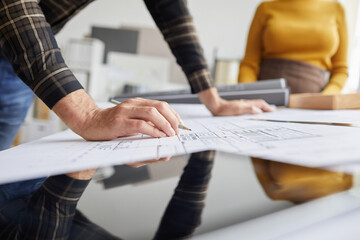 Close up of unrecognizable male architect drawing blueprints while working at desk in office, copy space