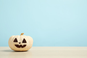 Pumpkin with scary face on light blue background, space for text. Halloween decor