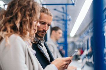 young couple discussing online news in a subway car .