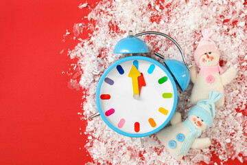 Alarm clock and snowmen in pile of snow on red background, flat lay with space for text. New Year...