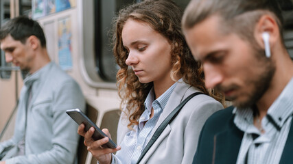 passengers using smartphones in the subway car .