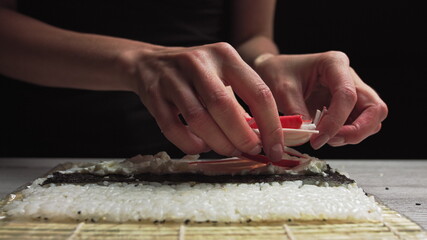 Close-up of Sushi Chef Hands puts crabs on a nori leaf and crab meat.Sushi making process.Rolls the sushi roll
