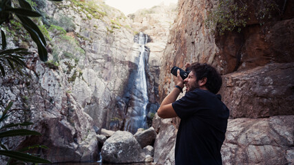 Frontal view of a young tourist photographing near Sa Spendula waterfall from below