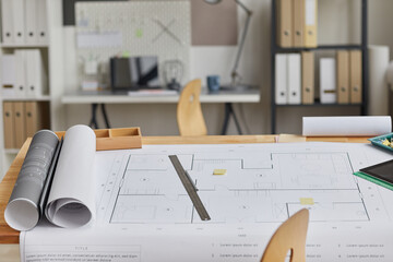 Background image of drawing table with blueprints and tools laid out in forground and architects...