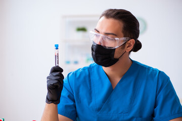 Naklejka premium Young male biochemist testing blood samples