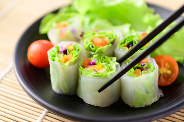 Colorful fresh vegetables salad spring roll eating with chopsticks, Healthy vegan food