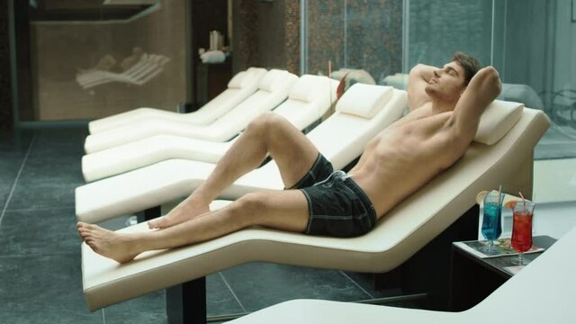 Sporty Man Relaxing At Wellness Resort. Sexy Guy Lying On Recliner In Hotel Spa.