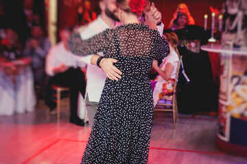 Couples dancing traditional latin argentinian dance milonga in the ballroom, tango salsa bachata lesson in the red lights, dance festival