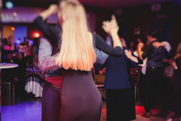 Couples dancing traditional latin argentinian dance milonga in the ballroom, tango salsa bachata lesson in the red lights, dance festival