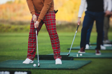Group of golfers practicing and training golf swing on driving range practice, men playing on golf...