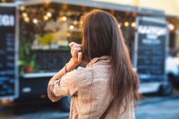 Girl ordering street food in colourful food truck van on food festival, summer sunny day