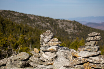 Fototapeta na wymiar Cairns on a small stone wall guide hikers on their way to the rocky summit of Cardigan Mountain