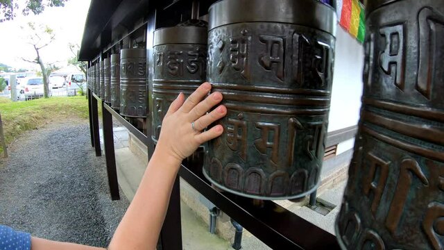 Slow motion video of  female tourist rotate weels in Kodaiji temple containing the Heart Sutra. Kyoto. Japan